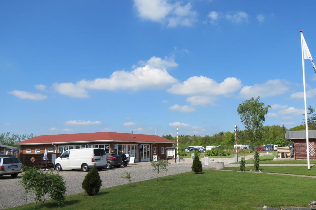 een gebouw met auto's geparkeerd op een parkeerplaats bij Holme Å Camping & Cottages in Hovborg