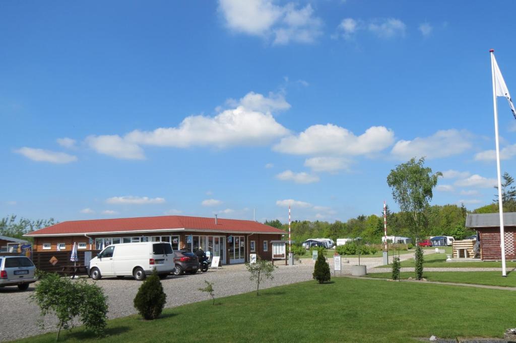 a building with cars parked in a parking lot at Holme Å Camping & Cottages in Hovborg