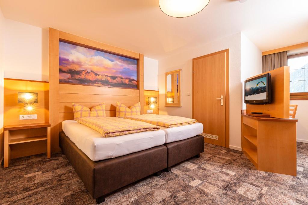 a hotel room with a bed and a television at Hotel-Garni Pramstraller in Mayrhofen