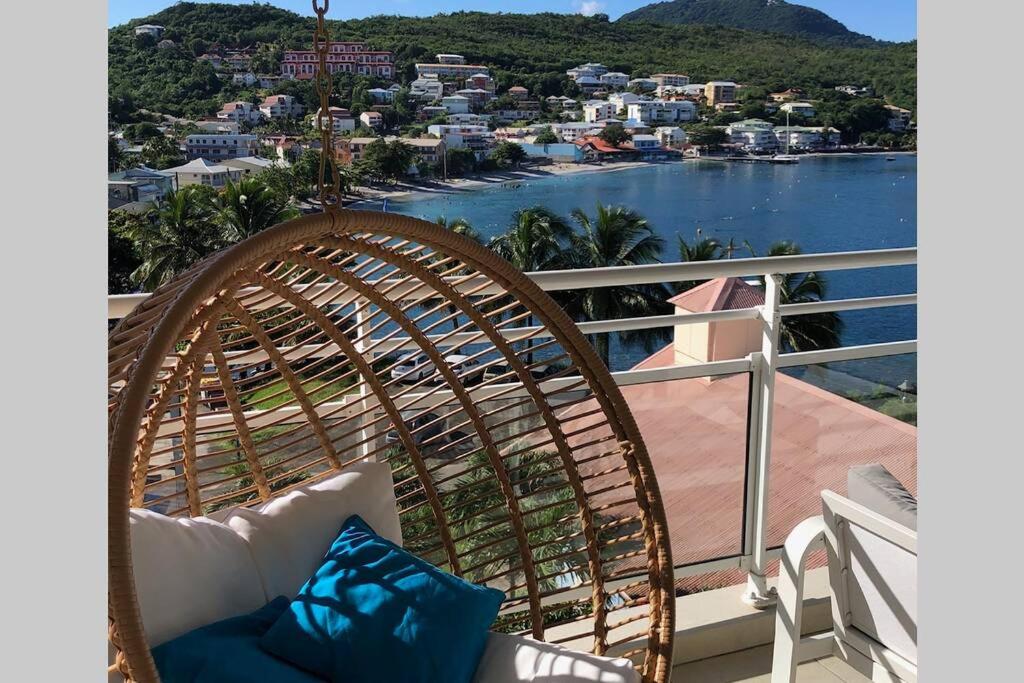 a rattan chair on a balcony with a view of the water at TROPICOOL in Les Trois-Îlets