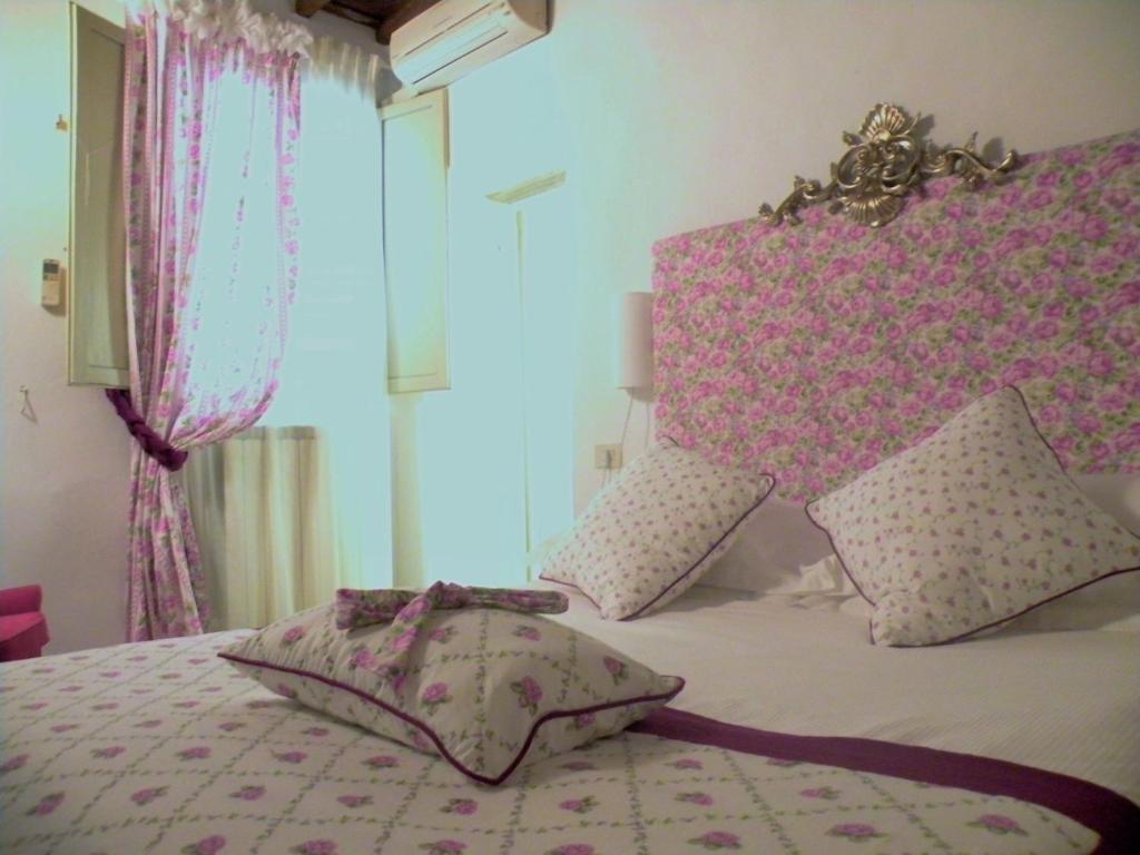 una camera da letto con letto, testiera rosa e cuscini di 20 Passi dal Duomo a Firenze