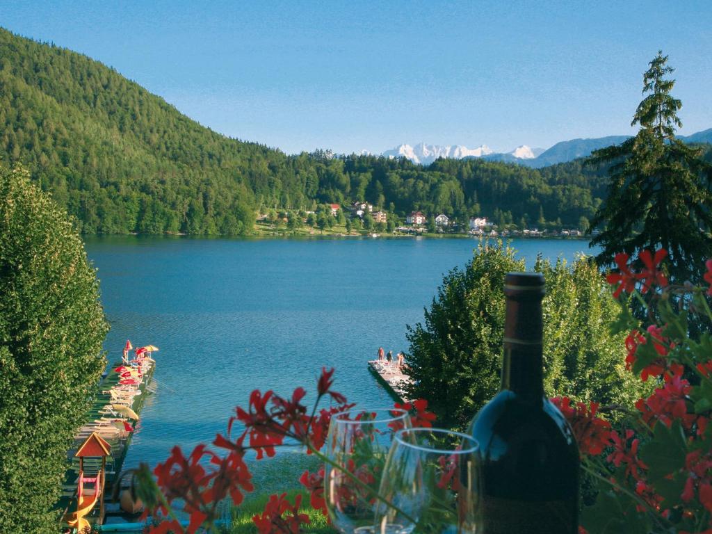 uma garrafa de vinho sentada numa mesa ao lado de um lago em Strandpension Seejuwel em Sankt Kanzian