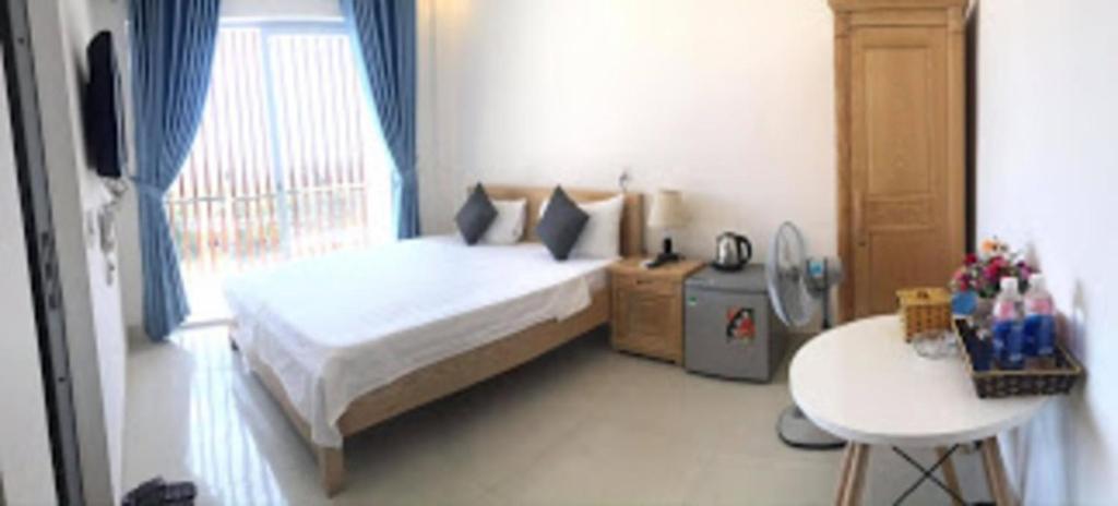 um quarto com uma cama, uma mesa e uma janela em Tuấn Anh 2 Hotel em Dong Hoi