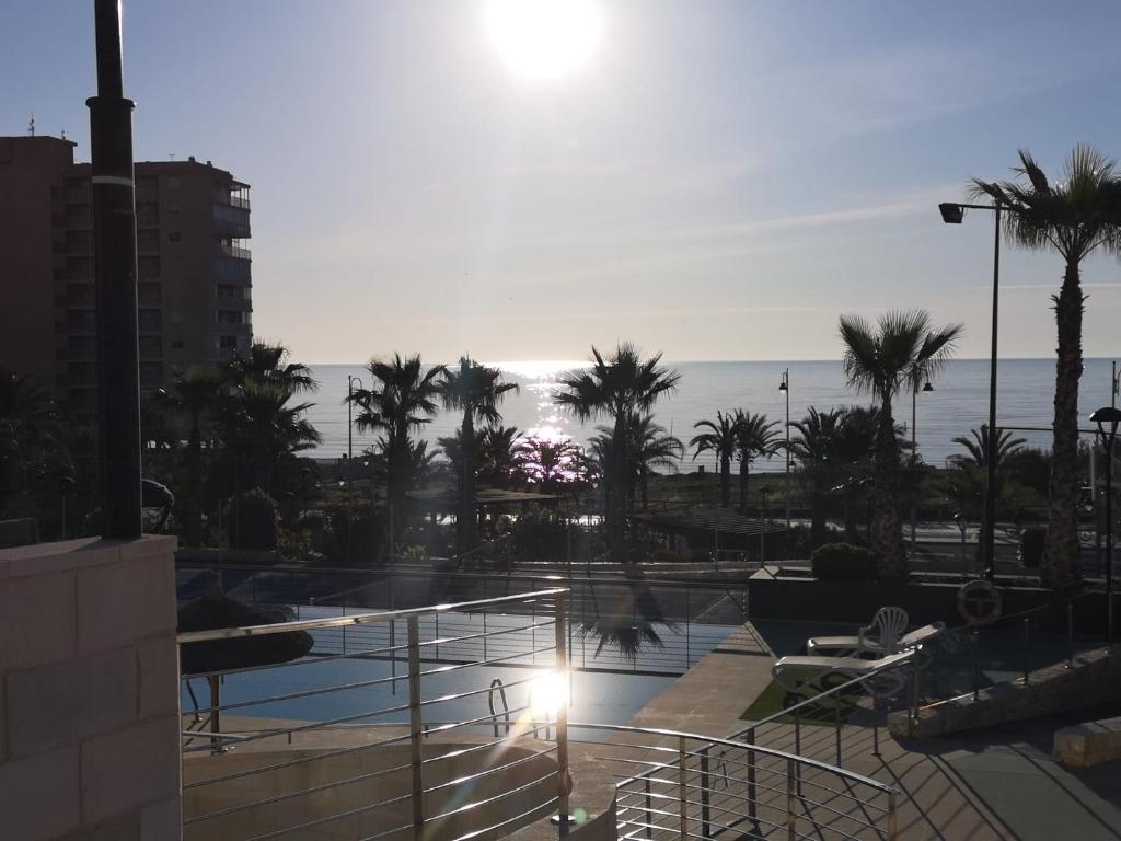 a view of a pool with palm trees and the ocean at Apartamento Postman in Arenales del Sol