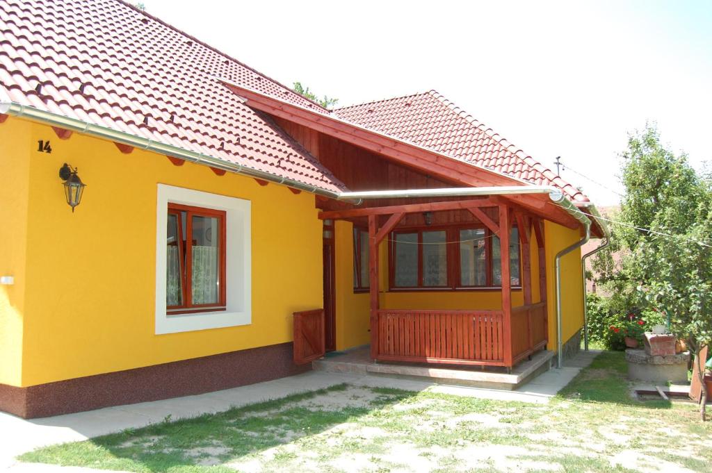 una pequeña casa amarilla con puerta roja en Csukavölgyi Apartman, en Visegrád