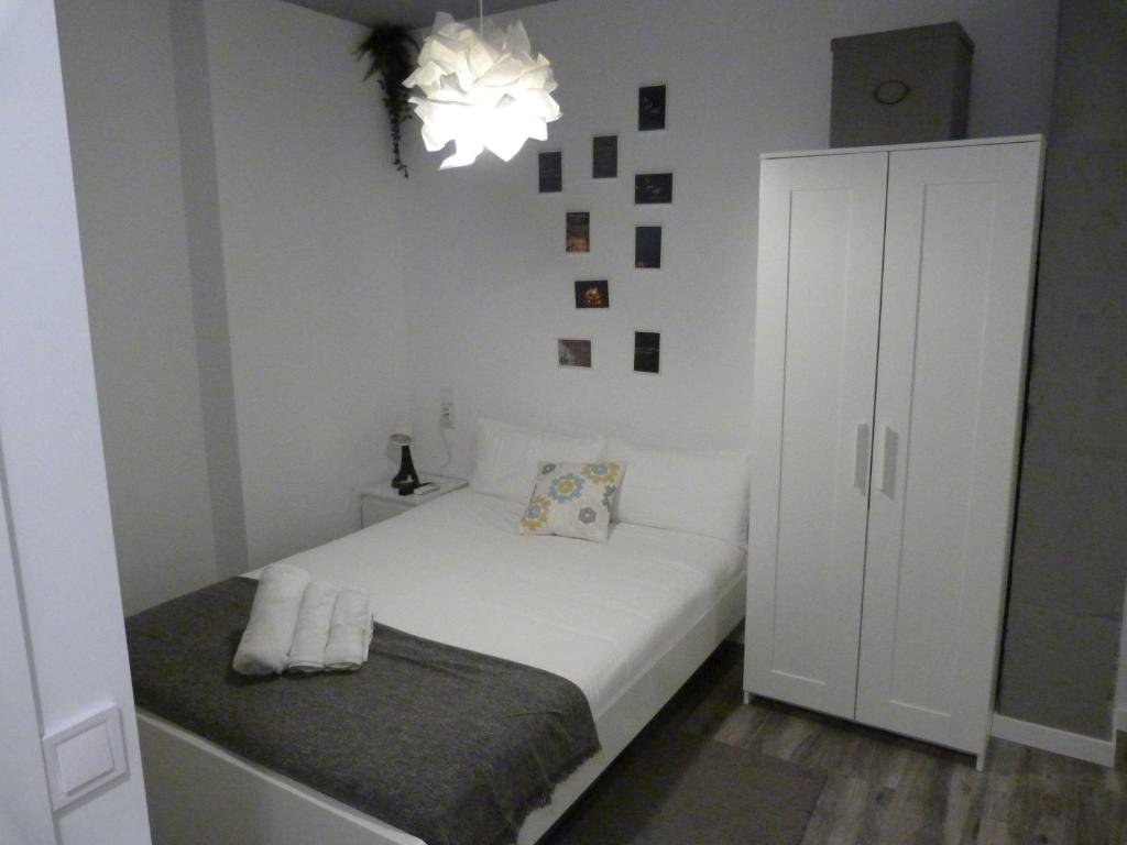 a small bedroom with a white bed and a chandelier at Intimo y Acogedor "algunos" con Bañera Hidromasaje in Valencia