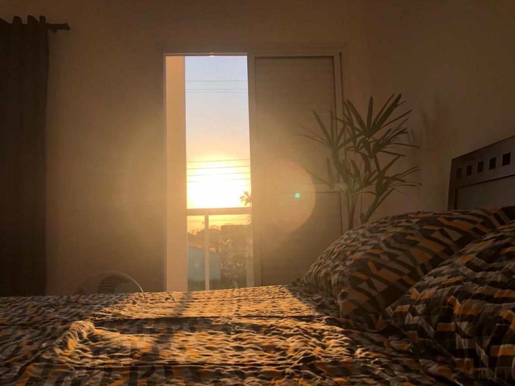 um quarto com uma cama e uma janela com o pôr-do-sol em Suíte privativa próxima ao Sesc 1 em Bertioga