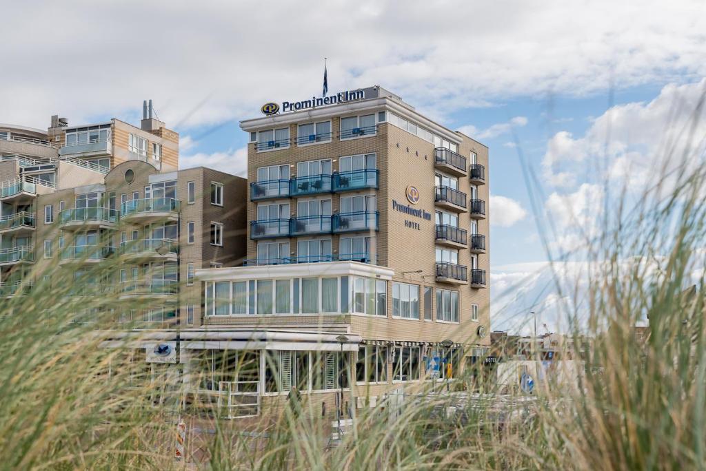a hotel building with mountains in the background at Prominent Inn Hotel in Noordwijk aan Zee