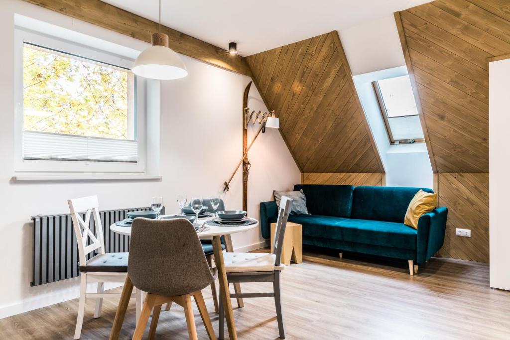 sala de estar con sofá azul, mesa y sillas en Apartament przy Bystrej Centrum Odkryj Zakopane en Zakopane