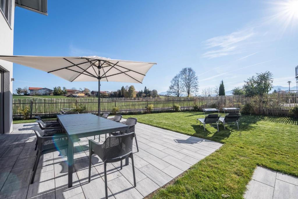 um pátio com uma mesa e um guarda-chuva em Design Ferienhaus 195qm em Breitbrunn am Chiemsee