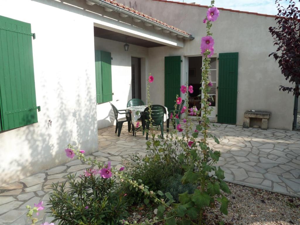- une terrasse avec une table, des chaises et des fleurs dans l'établissement Maison St Martin de Ré, à Saint-Martin-de-Ré