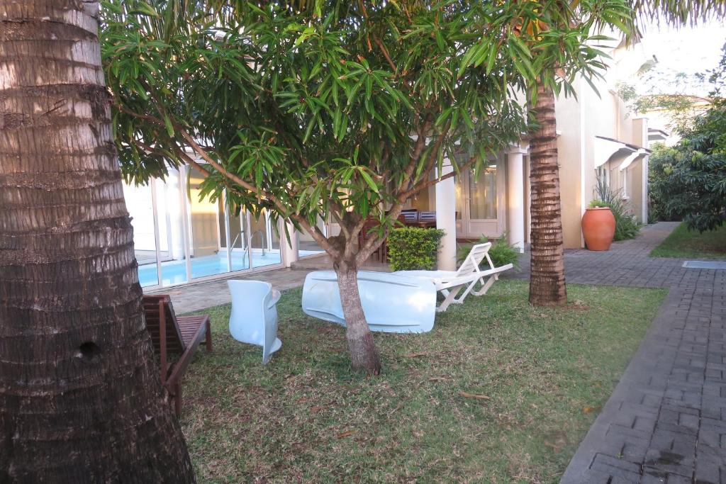 eine Gruppe Stühle und ein Baum im Hof in der Unterkunft Villa De Rouba in Blue Bay