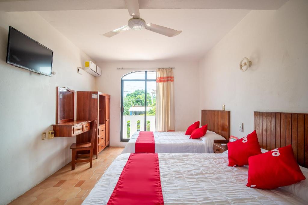 Habitación de hotel con 2 camas con almohadas rojas en OYO Hotel Arena Surf, Puerto Escondido, en Puerto Escondido