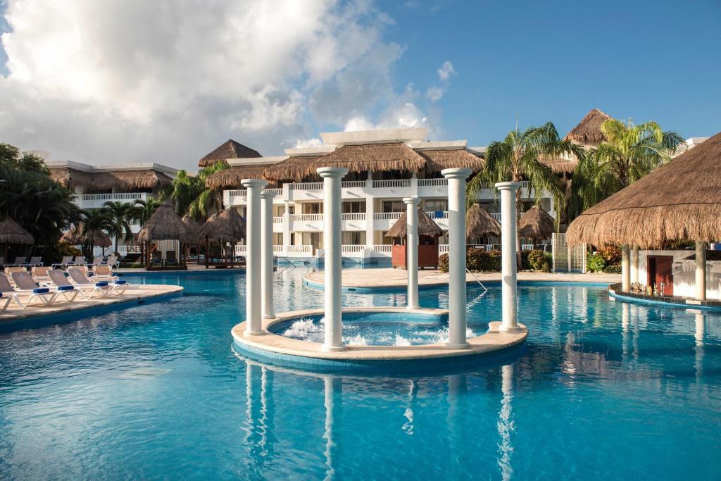 una piscina en un complejo con sillas y un edificio en Grand Sunset Princess - All Inclusive en Playa del Carmen