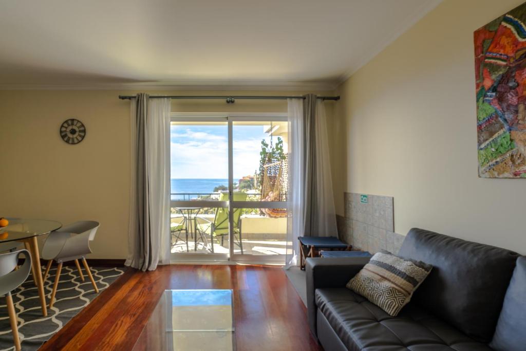 a living room with a couch and a view of the ocean at Ocean Breeze in Caniço