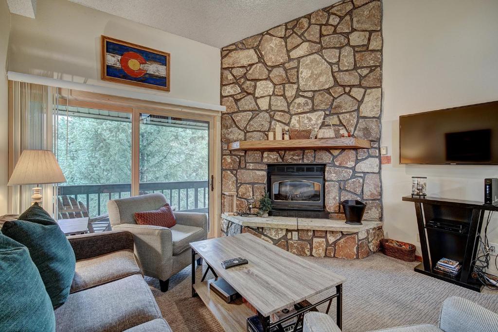 a living room with a stone wall with a fireplace at Atrium 304 in Breckenridge