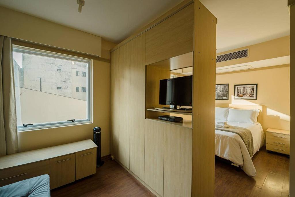 um quarto de hotel com uma cama e uma janela em BHomy Paulista Studio perto da Paulista RI106 em São Paulo