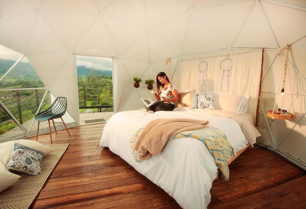 帕喬的住宿－Guaia Terra Glamping，坐在帐篷里的床上的女人