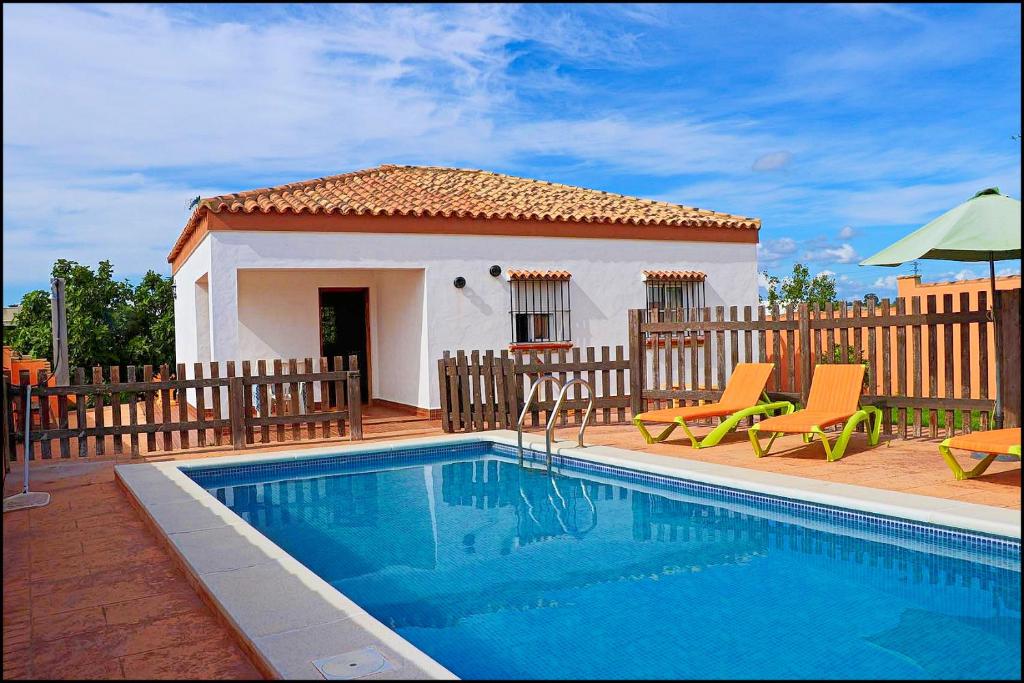 a villa with a swimming pool in front of a house at Chalet rústico Roche in Conil de la Frontera