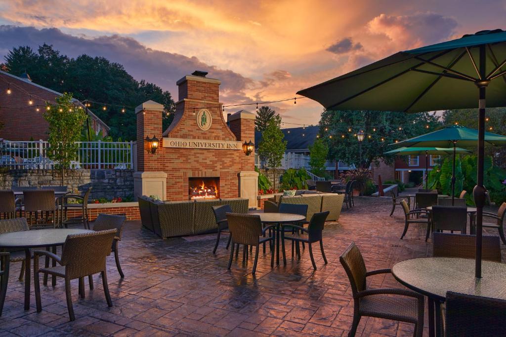 een patio met tafels en stoelen en een open haard bij Ohio University Inn and Conference Center in Athens