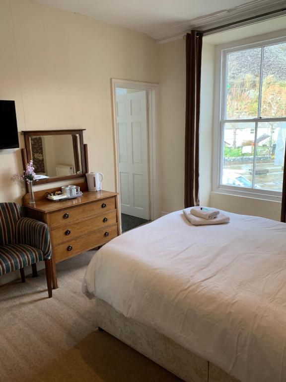 a bedroom with a bed and a dresser and a mirror at Queens Hotel in Blaenau-Ffestiniog