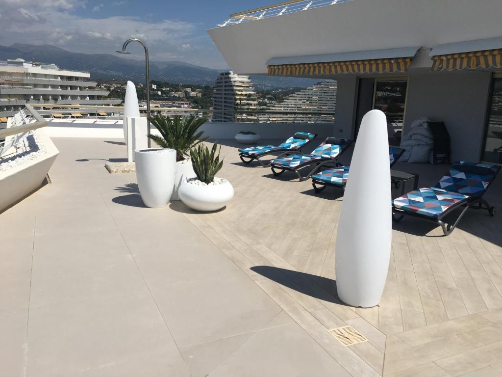 a rooftop patio with chairs and white columns on a building at Port Marina Baie des Anges in Villeneuve-Loubet