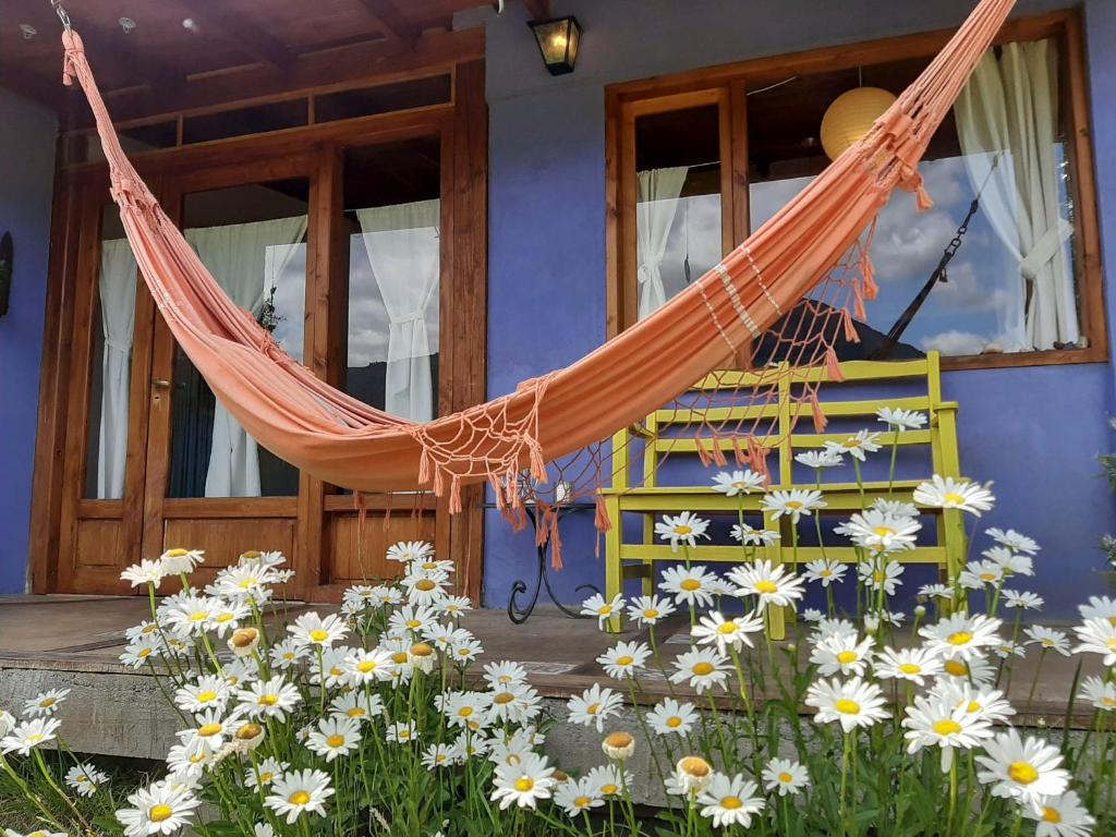 a hammock in front of a house with flowers at Cabañas Las Nativas in Lago Puelo