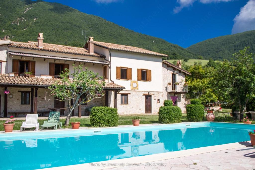 a villa with a swimming pool in front of a house at Agriturismo Santa Serena in Cerreto di Spoleto
