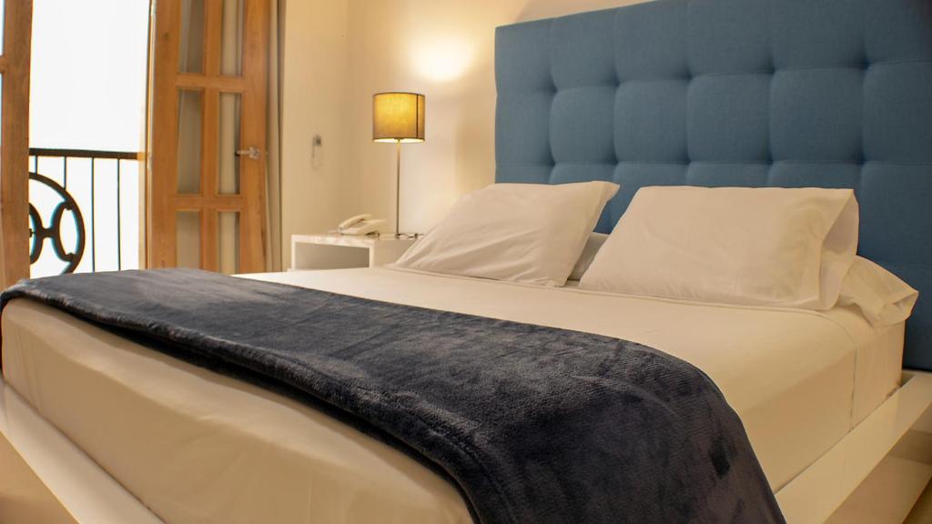 Schlafzimmer mit einem großen Bett mit blauem Kopfteil in der Unterkunft Hostal La Mercedes Boutique in Cali