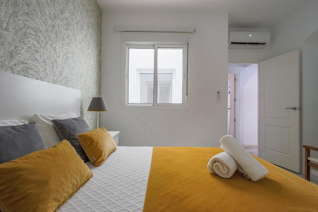 1 dormitorio con 1 cama grande con almohadas amarillas en Antonia díaz 2 4, en Sevilla