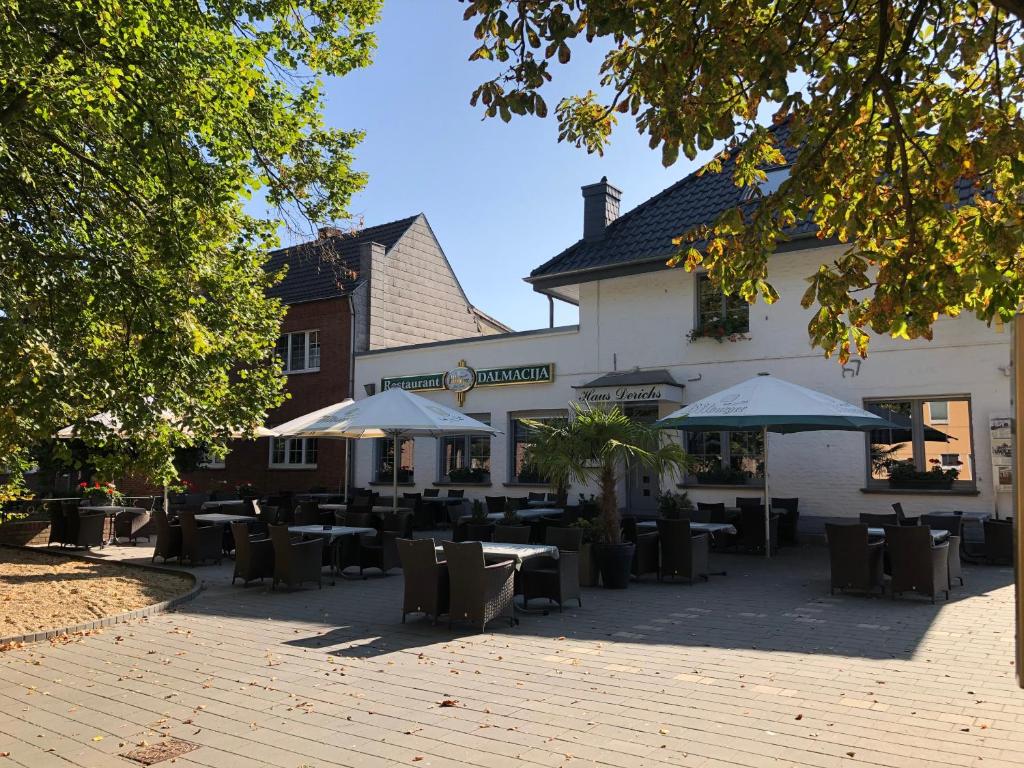 um restaurante com mesas e guarda-sóis em frente a um edifício em Hotel Restaurant Dalmacija em Gangelt
