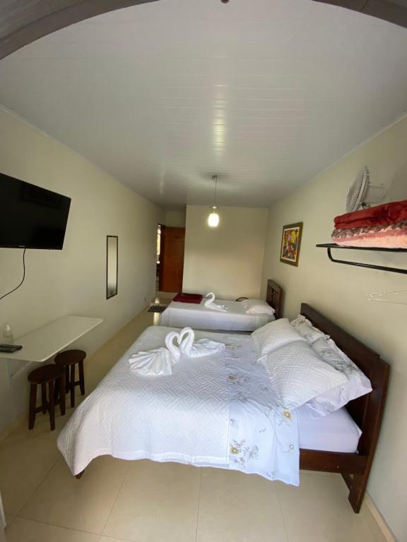 a bedroom with two beds with white sheets and a desk at Pousada Maciel in São Thomé das Letras