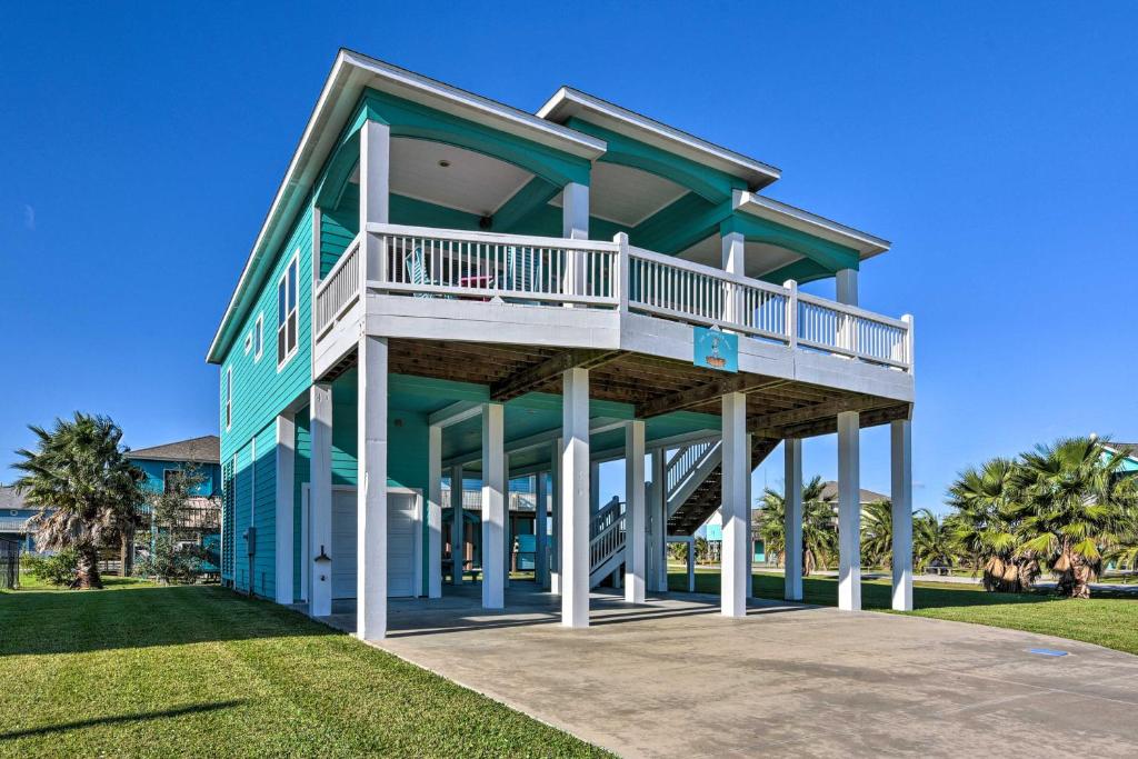 a blue house with a balcony on a lawn at Updated Crystal Beach Retreat with Deck and Fire Pit! in Bolivar Peninsula
