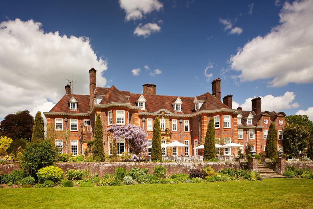 un gran edificio de ladrillo rojo con chimeneas. en Barnett Hill Hotel, en Guildford