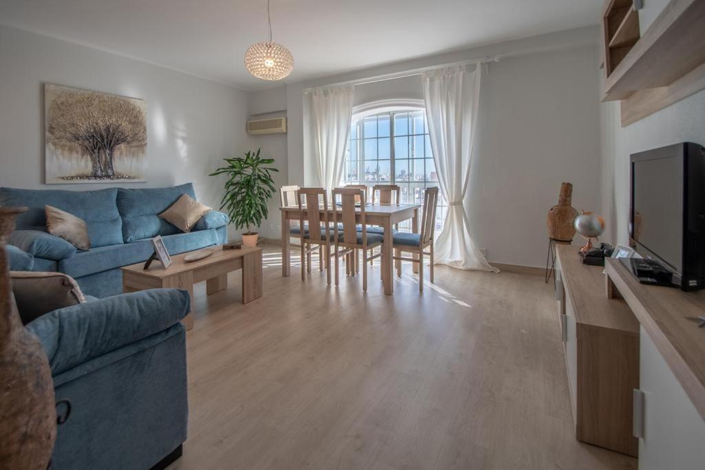 een woonkamer met een blauwe bank en een tafel bij Apartamento Fenicia con aparcamiento incluido Vistas al mar in Cádiz