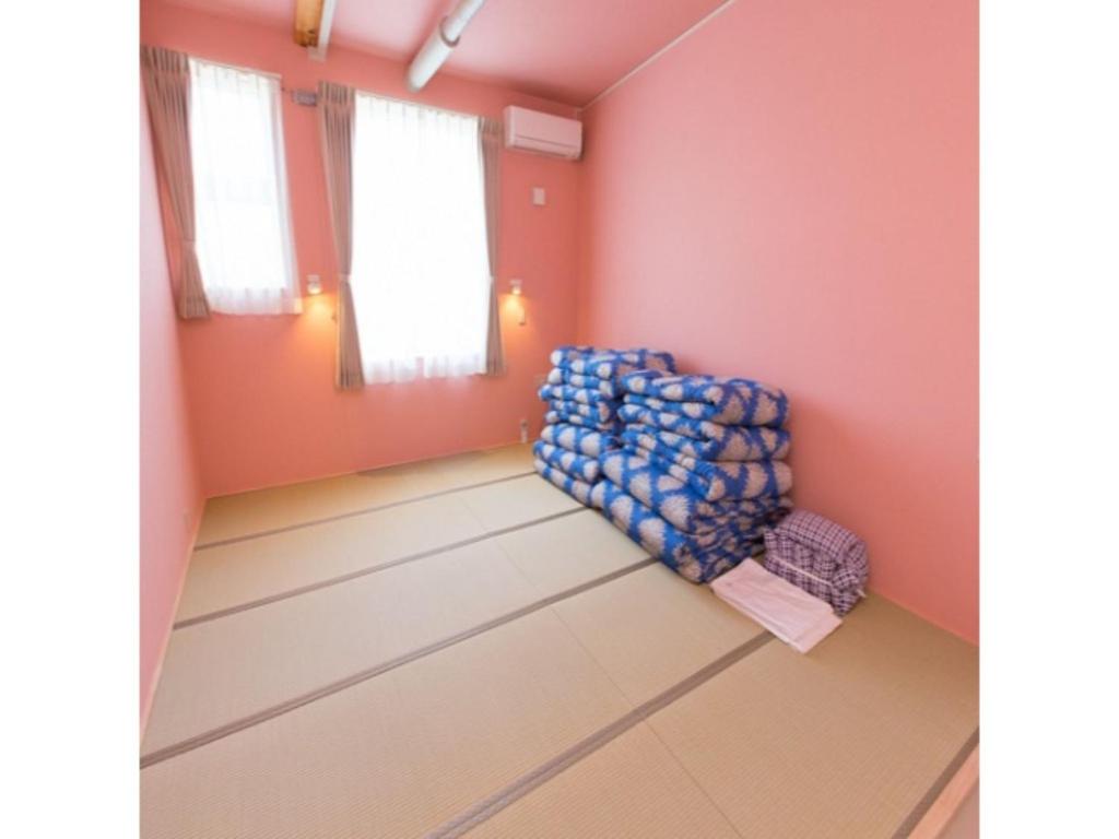 AkaishiにあるOGAL INN - Vacation STAY 01889vのピンクの壁の客室に青い椅子が備わります。