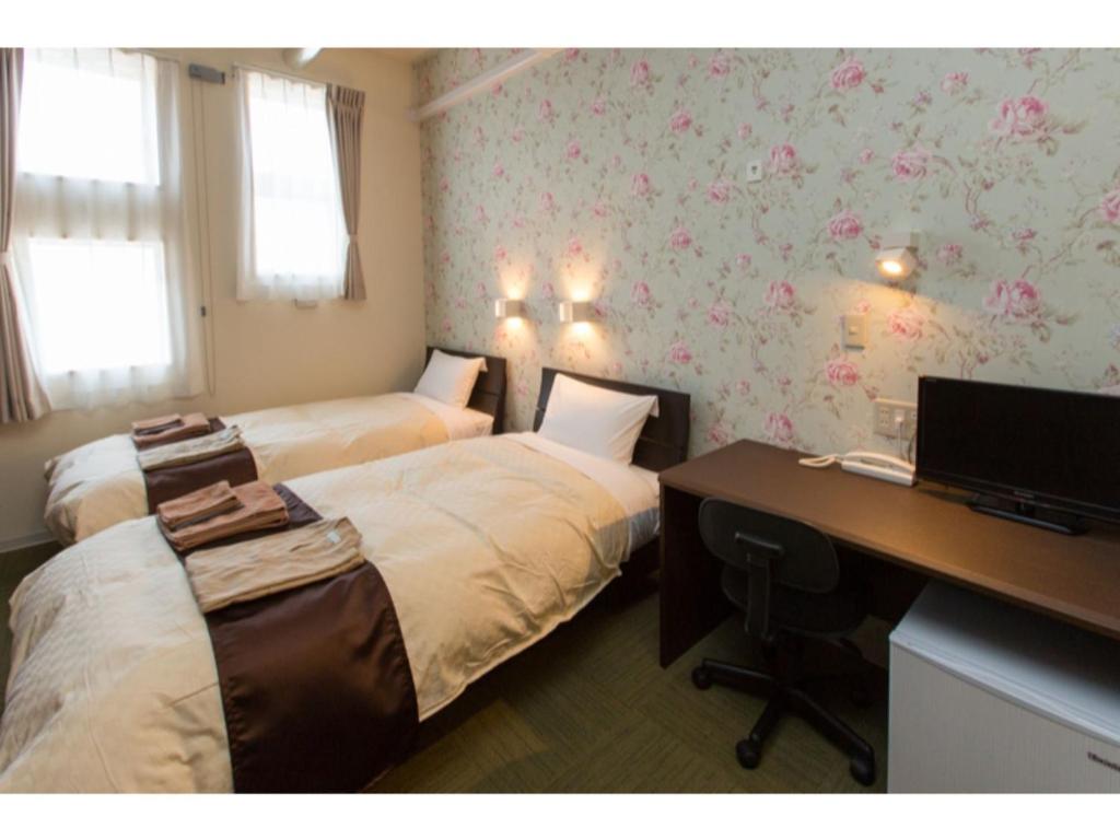 een hotelkamer met 2 bedden en een bureau met een computer bij OGAL INN - Vacation STAY 01855v in Akaishi