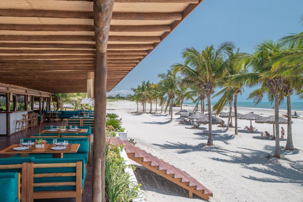 - un restaurant sur la plage avec des palmiers dans l'établissement Vila Selvagem Hotel Contemporaneo, à Fortim