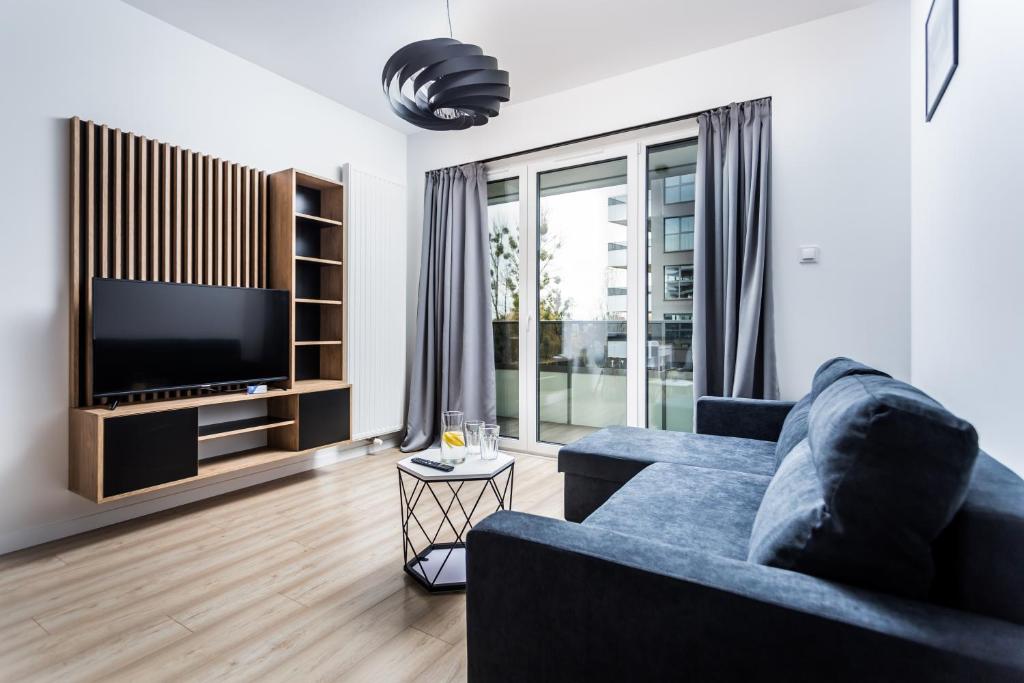 a living room with a blue couch and a tv at ResiNest Apartamenty Jurowiecka J17 in Białystok