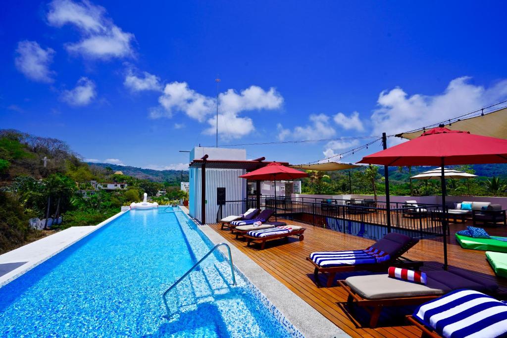 a swimming pool with chairs and umbrellas on a deck at Puerto Sayulita in Sayulita