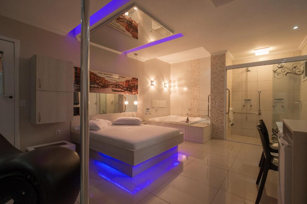 a bedroom with a bed and a shower and a tub at Motel Nix in Santa Maria