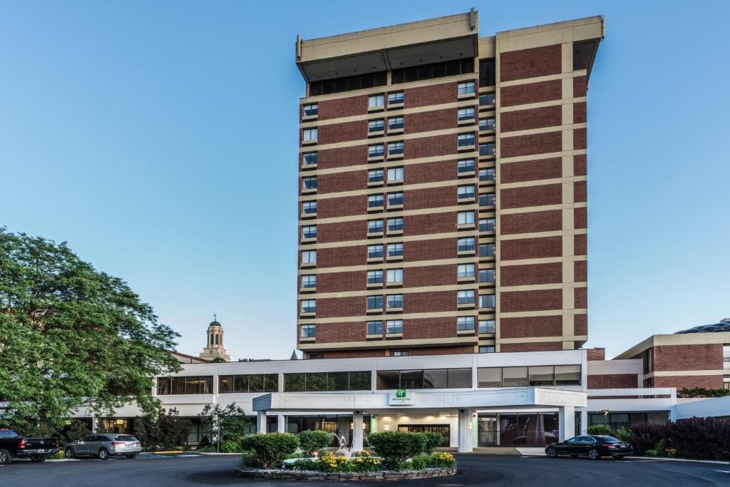 Holiday Inn & Suites Pittsfield-Berkshires, an IHG Hotel في بيتسفيلد: مبنى الفندق وامامه موقف سيارات