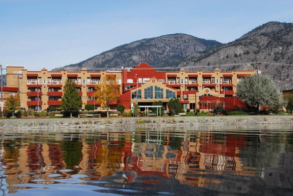 ein großes Gebäude mit einer Reflexion im Wasser in der Unterkunft Holiday Inn Hotel & Suites Osoyoos, an IHG Hotel in Osoyoos