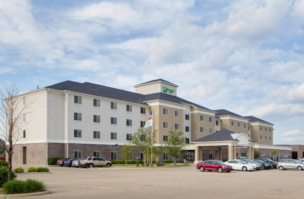 un hotel con coches estacionados en un estacionamiento en Holiday Inn Hotel & Suites Bloomington Airport, an IHG Hotel en Bloomington