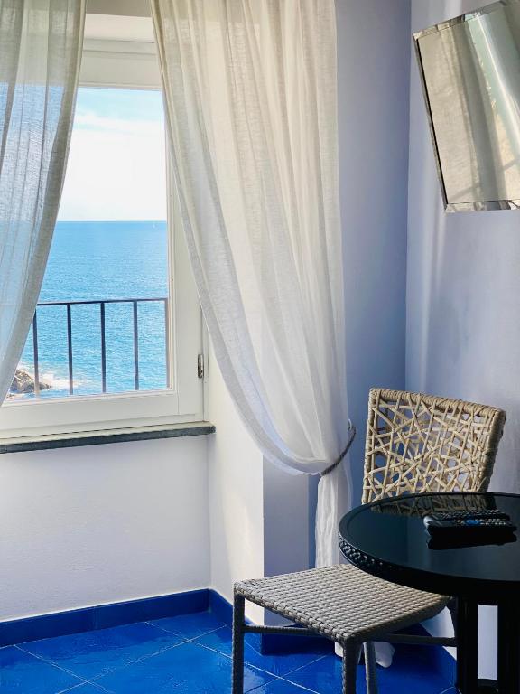 a room with a table and a window with the ocean at La Polena Camere Vernazza - Suite vista mare in Vernazza