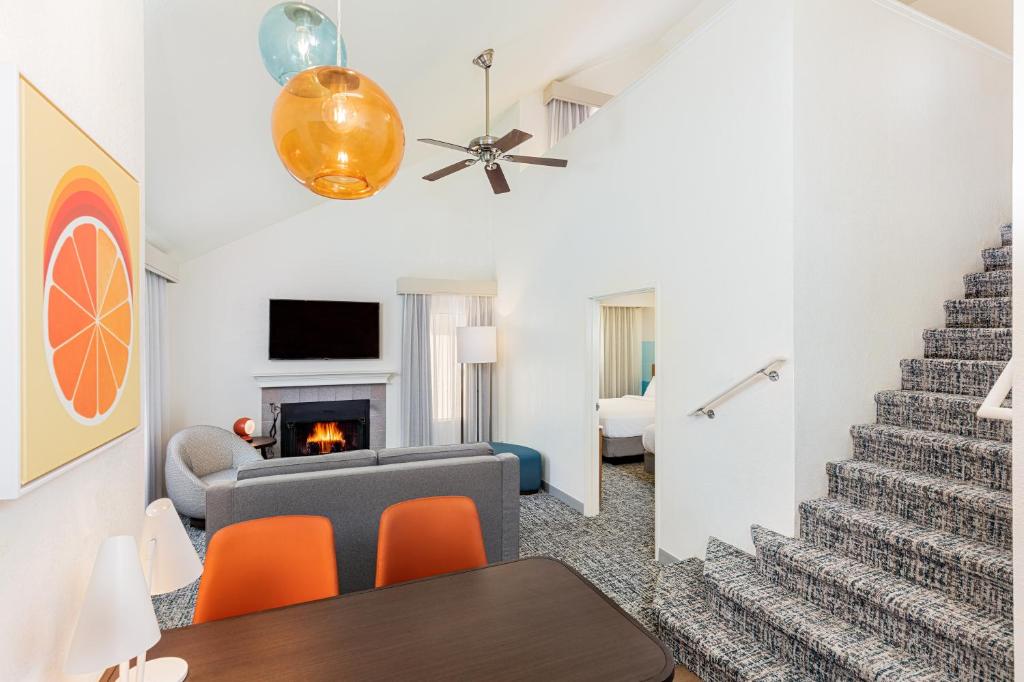 a living room with a staircase and orange chairs at Clementine Hotel & Suites Anaheim in Anaheim
