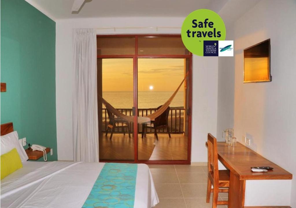 1 dormitorio con 1 cama y balcón con hamaca en Punta Zicatela Hotel - Adults Only en Puerto Escondido
