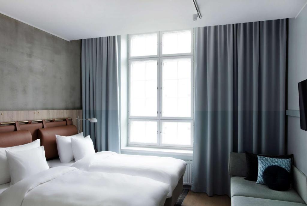 a bedroom with two beds and a window and a couch at Radisson Blu Seaside Hotel, Helsinki in Helsinki
