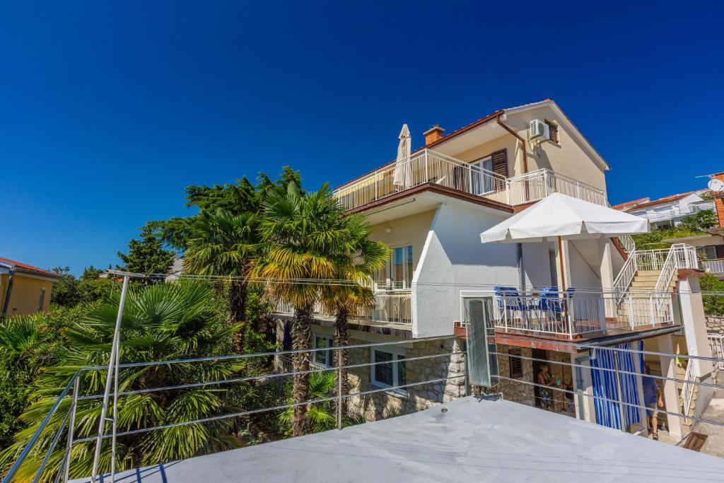 een huis met een balkon en palmbomen bij Apartments Danica in Dramalj