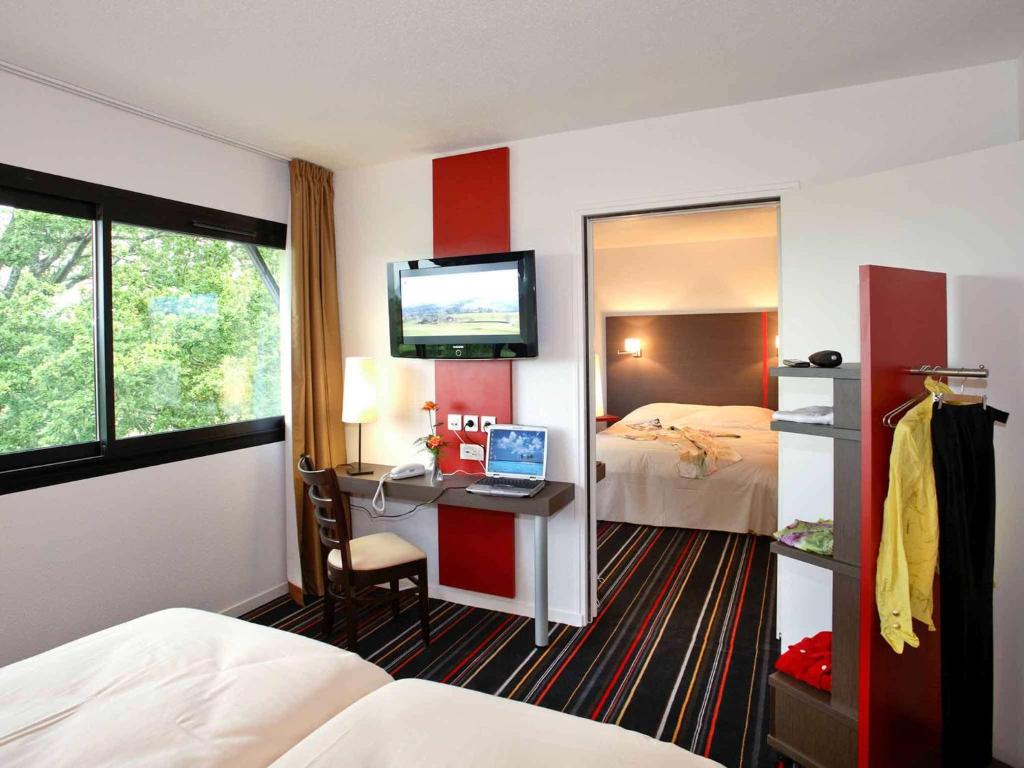a hotel room with a bed and a desk with a computer at ibis Styles Segre in Segré